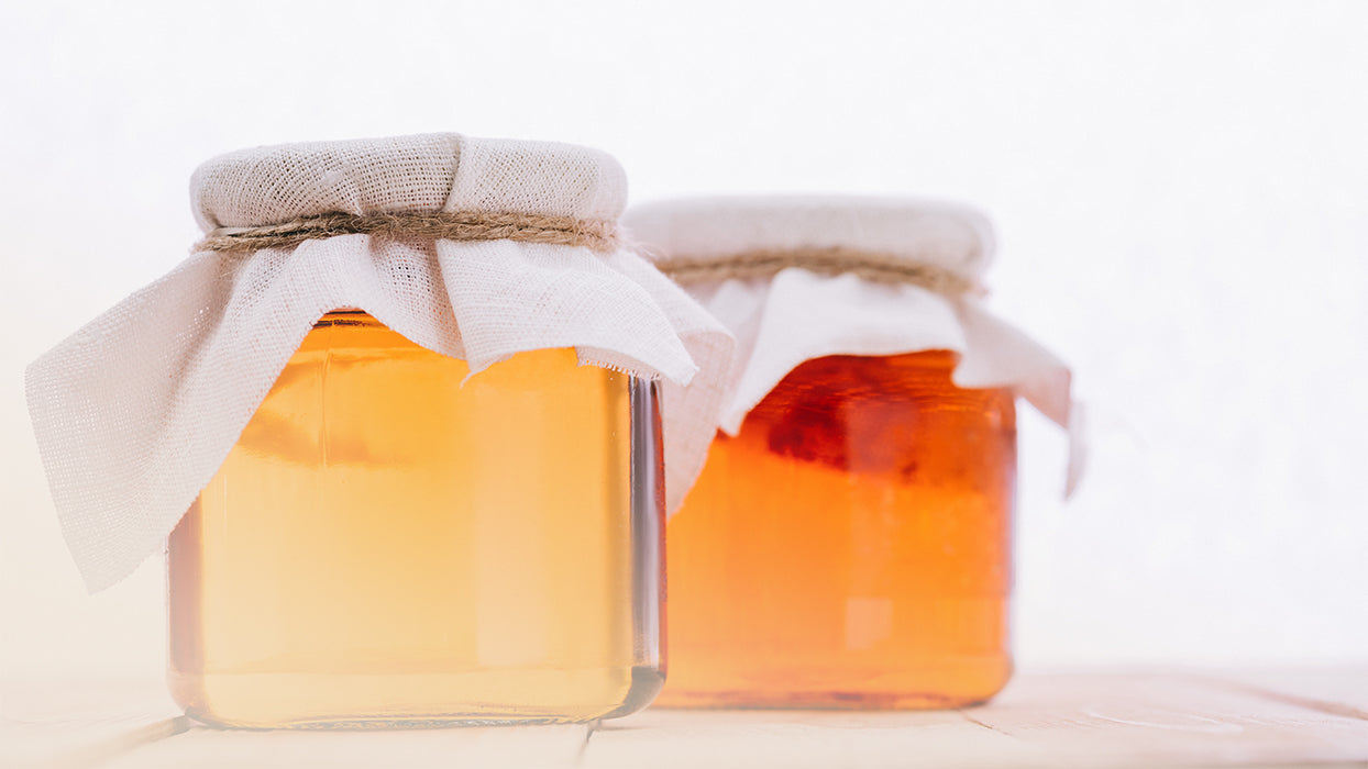 Zwei Einmachglaeser mittelgross mit Kombucha mit Tuechern abgedeckt