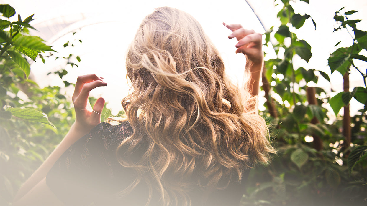 Frau lange blonde Haare von Planzen umgeben