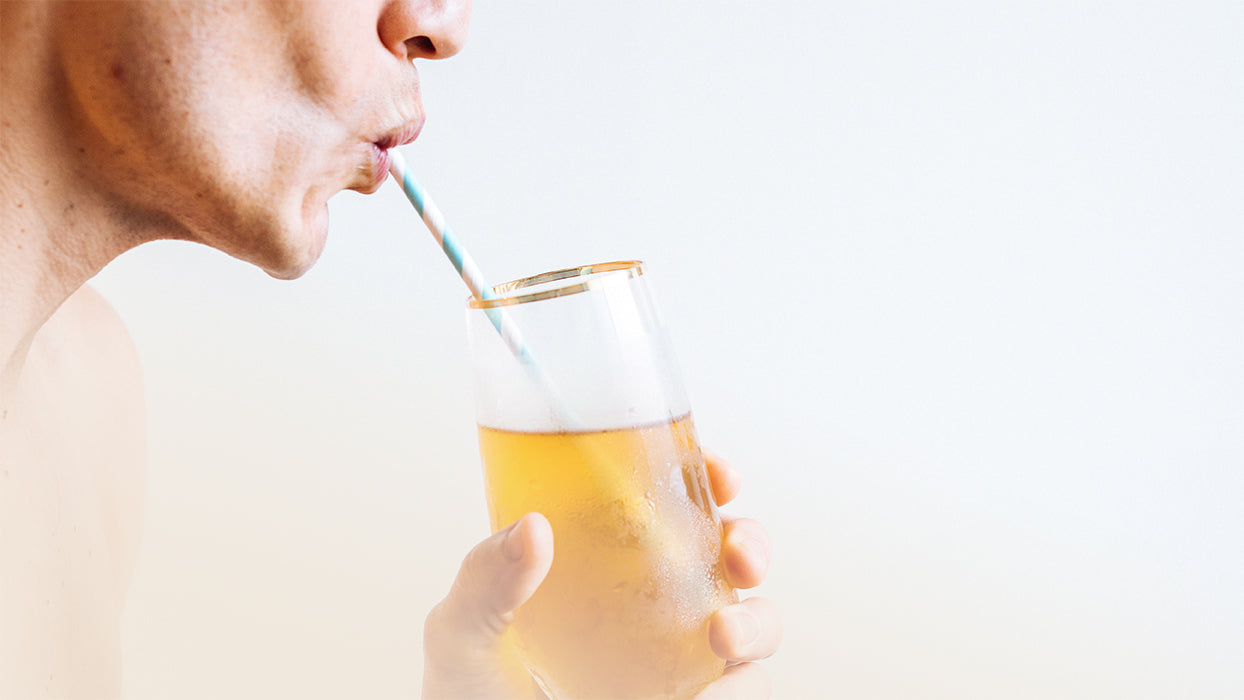 Frau zieht am Strohhalm Kombucha aus Glas